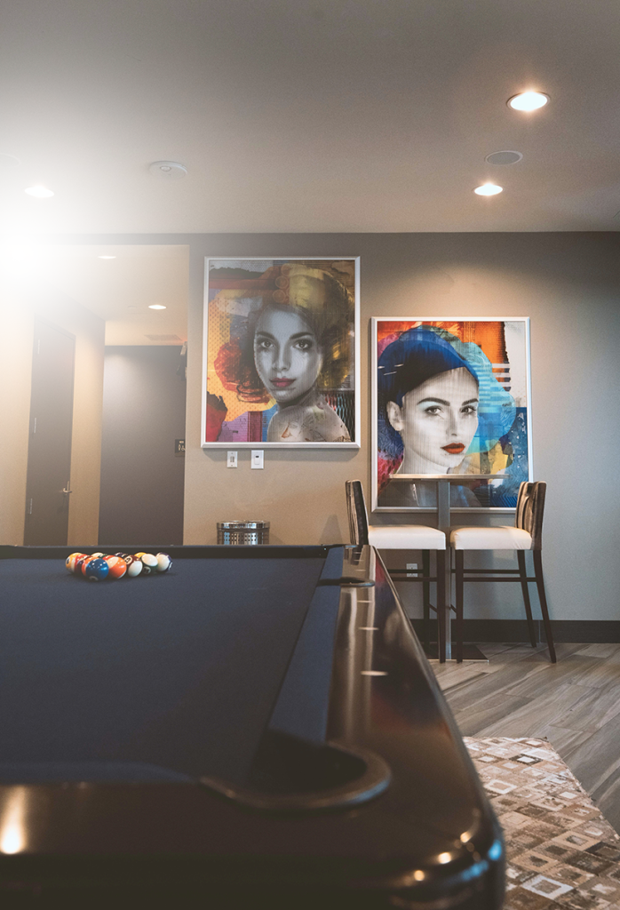 Game room with pool table, colorful portrait artwork, and a bistro table with two chairs